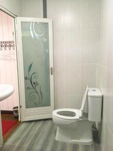 a bathroom with a toilet and a glass door at Banpak Suankaew Talaynoi in Phatthalung