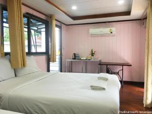 Un dormitorio con una gran cama blanca y una mesa en Banpak Suankaew Talaynoi en Phatthalung