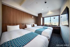 une chambre d'hôtel avec trois lits et une fenêtre dans l'établissement HOTEL AMANEK Asakusa Ekimae, à Tokyo
