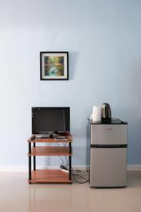 uma mesa com uma televisão e um frigorífico num quarto em Jasmin's Room Rental em Moalboal