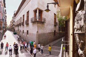 Un gruppo di persone che camminano lungo una strada accanto a un edificio di Travelers Rest a Pamplona