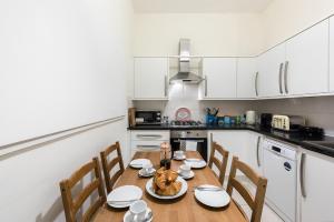 a kitchen with a wooden table with chairs and a table at Heart of Ealing Apartment with Garden in London