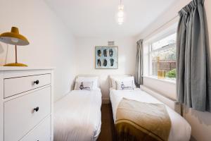 two twin beds in a room with a window at Heart of Ealing Apartment with Garden in London