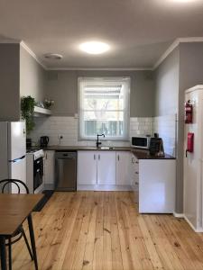 a kitchen with white cabinets and a wooden floor at Cute and Cosy II - Events, Workers, Getaways. in Murray Bridge