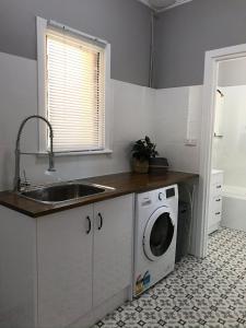 a kitchen with a sink and a washing machine at Cute and Cosy II - Events, Workers, Getaways. in Murray Bridge