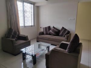 sala de estar con 2 sofás y mesa de cristal en Suvarna Compact, en Mysore