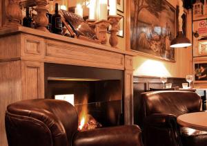 - une cheminée dans une pièce avec deux chaises et une table dans l'établissement The Tuscanian Hotel, à Lucques