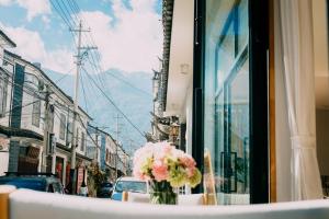 un vase de fleurs assis sur une table dans une fenêtre dans l'établissement Dali Blocks · Cafe & Travel Hotel, à Dali