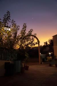 an arch in a yard with a sunset in the background at Seven Garden Alhada Suites in Al Hada