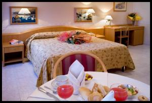 キアーヴァリにあるホテル モンテ ローザのベッドとテーブル(食べ物付)が備わるホテルルームです。