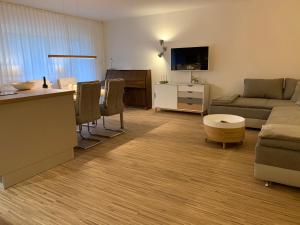 ein Wohnzimmer mit einem Sofa und einem Tisch sowie eine Küche in der Unterkunft Moderne Ferienwohnung nahe SWR und Golfplatz in Baden-Baden