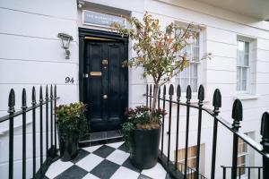 a black door on a white house with plants at The Warwick By Aura Collection in London