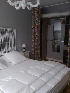 a large white bed in a bedroom with a chandelier at L' entre mer et falaise in Le Tréport