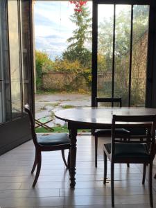 einen Tisch und Stühle in einem Zimmer mit Fenster in der Unterkunft Le studio du botaniste in Giverny