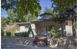 a small house with a stone fence in front of it at River country in Kalavrita