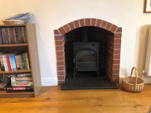 una chimenea de ladrillo en la sala de estar con un estante de libros en The Oaks en Warminster