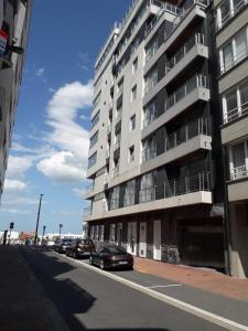 a street with cars parked in front of a tall building at Appartement met zicht op zee in Knokke-Heist