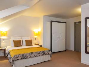 um quarto com uma cama com lençóis amarelos e brancos em Mercure Rambouillet Relays Du Château em Rambouillet