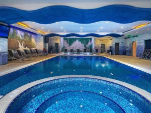 a large swimming pool in a hotel with chairs at Mercure Corniche Al Khobar in Al Khobar