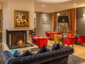 a living room with a couch and a fireplace at Mercure Rambouillet Relays Du Château in Rambouillet