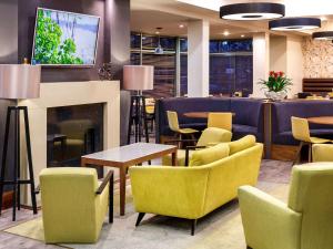 a restaurant with yellow chairs and tables and a fireplace at Mercure Sheffield Parkway in Sheffield