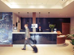 a man in a suit standing at a counter in a lobby at Mercure Sheffield Parkway in Sheffield