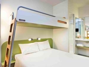 ibis budget Lyon Est Chaponnay في تشابوناي: غرفة نوم مع سرير بطابقين وسرير أبيض