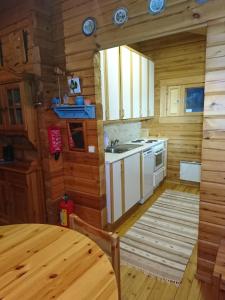 a kitchen in a log cabin with a sink and a stove at Kuhajärven Suviranta cottage in Vihtavuori