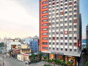 ein hohes rotes Gebäude in einer Stadt mit Gebäuden in der Unterkunft Ibis Saigon Airport in Ho-Chi-Minh-Stadt