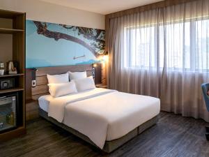 een slaapkamer met een groot bed en een groot raam bij Novotel Sorocaba in Sorocaba