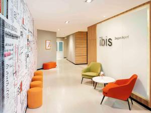 a waiting room with chairs and a table and a wall at Ibis Saigon Airport in Ho Chi Minh City