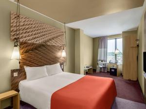 a hotel room with a large bed and a desk at ibis Moscow Domodedovo Airport in Domodedovo