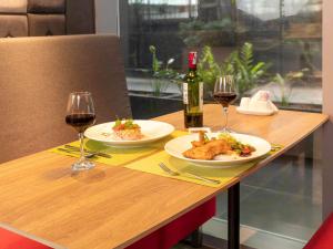 a table with two plates of food and two glasses of wine at Ibis Saigon Airport in Ho Chi Minh City