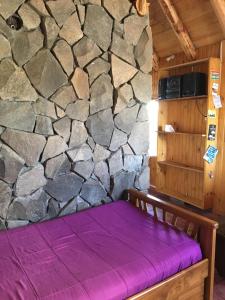 uma cama num quarto com uma parede de pedra em Cabaña en Caviahue em Caviahue