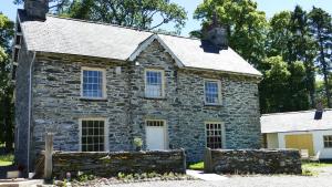 una antigua casa de piedra con una pared de piedra en cosy ground floor disabled friendly room in farm house, en Bala