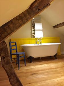 La salle de bains est pourvue d'une baignoire blanche et d'une chaise bleue. dans l'établissement The Coach House, à Austwick