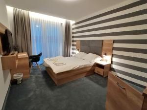 a bedroom with a bed and a desk and a television at LAKE VIEW Apartamenty in Brodnica