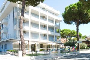 ein großes weißes Gebäude mit Bäumen davor in der Unterkunft Residence Quadrifoglio in Cervia