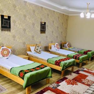 three beds in a room with wooden floors and walls at Guest House EtnoDom in Jalal-Abad