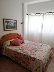 1 Schlafzimmer mit einem Bett mit einer Blumendecke und einem Fenster in der Unterkunft Apartamentos Aguas Verdes in Las Palmas de Gran Canaria