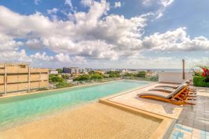 a swimming pool with chaise lounge chairs on top of a building at Sunset 203 at Riva in Playa del Carmen