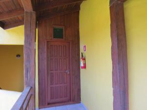 a red door in a room with a yellow wall at Pousada Nusa Dua Maresias in Maresias