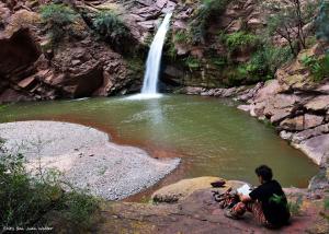 a man sitting on a rock in front of a waterfall at Viajeros in Salta