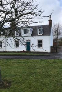 a white house with a blue door on a street at Mulberry Cottage, Bowden in Melrose