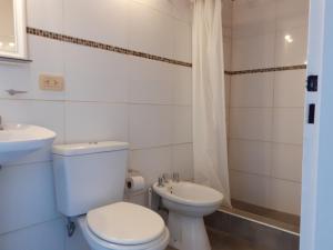a white bathroom with a toilet and a sink at ENCANTOS DE MENDOZA Apartments in Mendoza