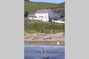 a group of people in the water at a beach at Nolton Haven Farmhouse Apartment, Sea Views in Haverfordwest