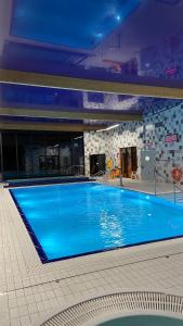 a large blue swimming pool in a building at Apartament Eden 5 Mórz Basen&Spa in Sianozety