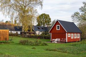 um celeiro vermelho com um telhado preto num quintal em Brösarp Källagården Vedboden em Brösarp