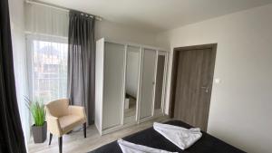 a bedroom with a bed and a chair and a window at Apartament Eden 5 Mórz Basen&Spa in Sianozety