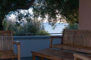 dwie drewniane ławki siedzące pod drzewem na balkonie w obiekcie Villetta Fenosa w mieście Marina di Camerota